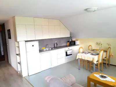 a kitchen with white cabinets and a table and a dining room at Apartments Janjusevic in Bled