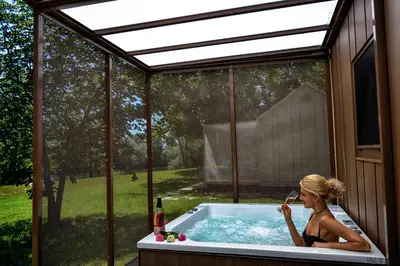 a woman sitting in a hot tub in a backyard at MAGNOLIA HOUSE by the RIVER BB in Primostek