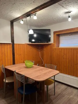 a wooden table with chairs and a television on a wall at Cosy apartment in Ljubljana in Šentvid