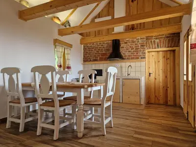 a kitchen with a wooden table and chairs at Izba in Lendava