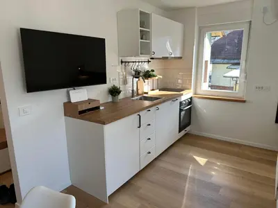 a kitchen with white cabinets and a flat screen tv at Lamant Apartment Cerkno in Cerkno