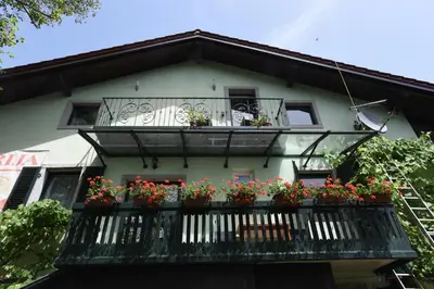a building with a balcony with flowers on it at Fedrig Hostel rooms Apartment for 10 in Kobarid