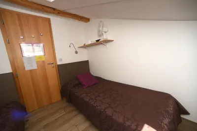 a small bedroom with a bed and a wooden door at Fedrig Hostel rooms Apartment for 10 in Kobarid