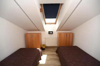 a attic room with two beds and a window at Fedrig Hostel rooms Apartment for 10 in Kobarid
