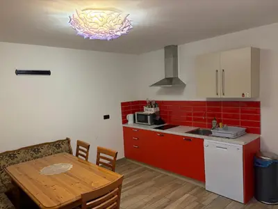 a kitchen with a table and a kitchen with red tiles at Fedrig Hostel rooms Apartment for 10 in Kobarid