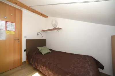 a bedroom with a bed and a wooden door at Fedrig Hostel rooms Apartment for 10 in Kobarid