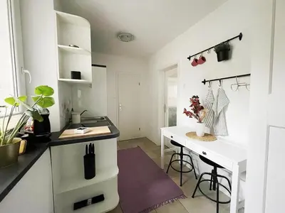 a white kitchen with a desk and a table at Manca's Apartment with Free Parking in Ljubljana