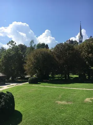 a green park with a church in the background at Apartment Center in Bled
