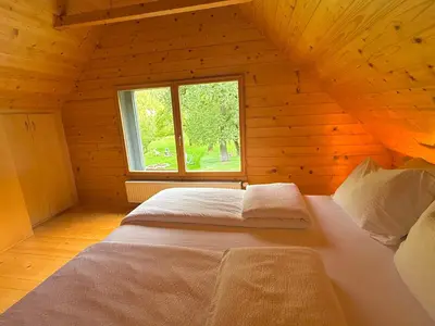 a bed in a wooden room with a window at Soča Village in Soča