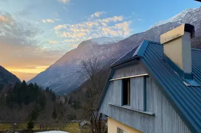 a house with a blue roof with mountains in the background at Soča Village in Soča