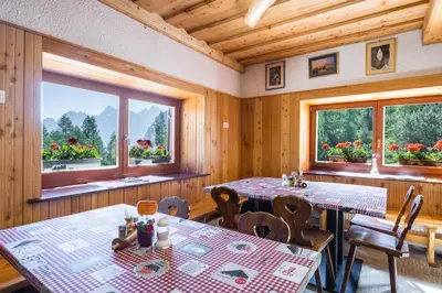 a dining room with two tables and two windows at Poštarski dom on Vršič in Kranjska Gora