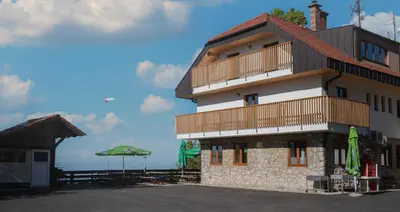 a building with a balcony and a table and umbrella at Tončkov dom na Lisci in Sevnica