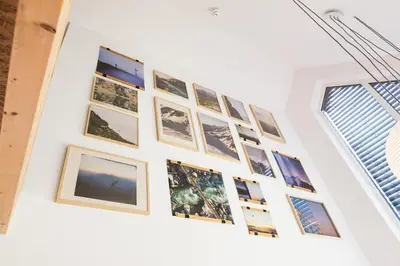 a wall of pictures on a white wall at Nomad 27 in Bovec