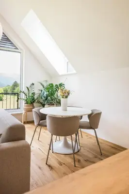 a white dining room with a table and chairs at Nomad 27 in Bovec