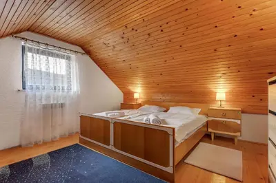 a large bed in a room with a wooden ceiling at Urban Escape Cottage in Ljutomer