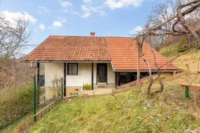 a small white house with an orange roof on a hill at Urban Escape Cottage in Ljutomer