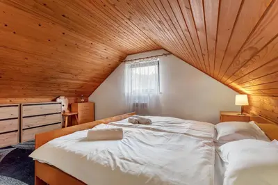 a bedroom with a large bed with a wooden ceiling at Urban Escape Cottage in Ljutomer