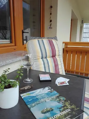 a table with a book and a wine glass and a chair at Apartments Grudnik in Kranjska Gora