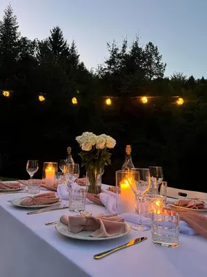 a white table with candles and wine glasses and flowers at Cosy getaway in raw nature in Šentjur