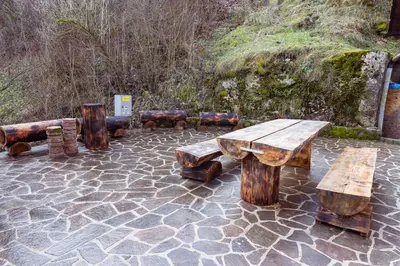 a group of wooden tables and benches on a patio at Apartment Grič with Sauna in Stari Trg pri Ložu
