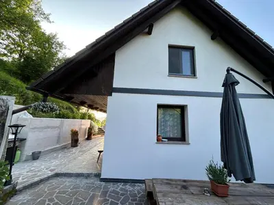 a white house with an umbrella on a patio at Apartment Grič with Sauna in Stari Trg pri Ložu
