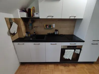 a small kitchen with white cabinets and a sink at Apartma Valerija in Zreče