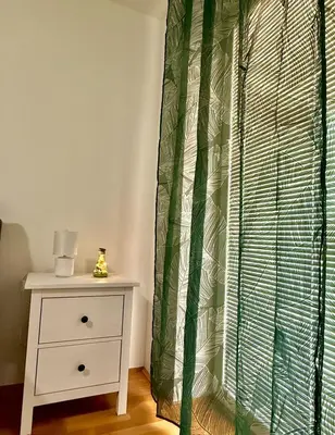 a bedroom with a dresser and a green and white curtain at Sunflower Apartment Moravske Toplice in Moravske Toplice