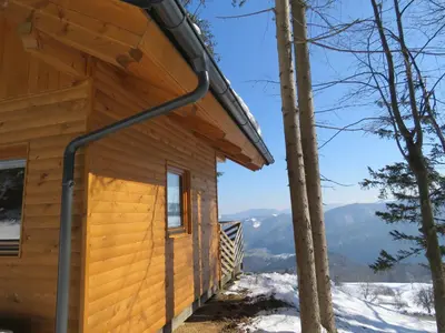 a log cabin in the snow with mountains in the background at Turistična kmetija Okršlan in Škofja Loka