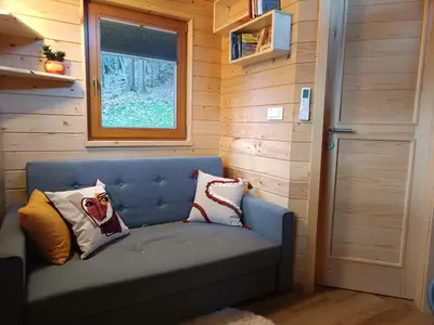 a blue couch with pillows in a tiny house at Turistična kmetija Okršlan in Škofja Loka