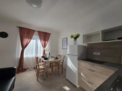 a kitchen with a table with chairs and a refrigerator at Apartment Barje II, bright&sunny, private parking in Ljubljana