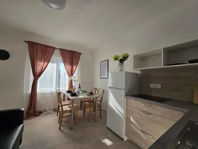a kitchen with a table with chairs and a refrigerator at Apartment Barje II, bright&sunny, private parking in Ljubljana