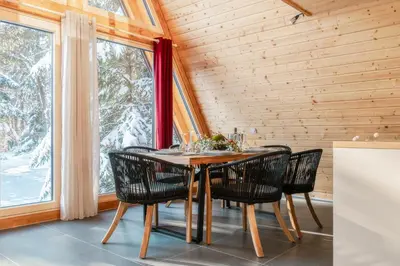 a dining room with a table and chairs and windows at Pohorska Gozdna Vila in Pohorje