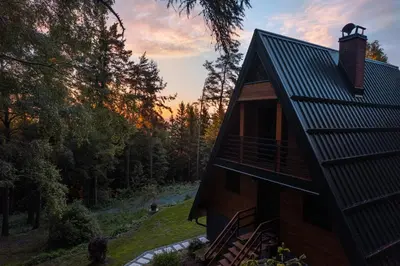 a house in the woods with the sunset in the background at Pohorska Gozdna Vila in Pohorje