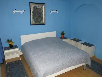 a blue bedroom with a bed and two night stands at Blumauer Apartments in Ljubljana