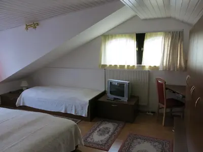 a bedroom with two beds and a tv and a desk at Blumauer Apartments in Ljubljana