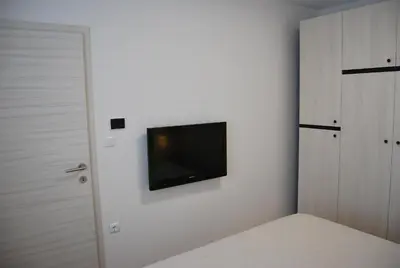 a bedroom with a tv on a white wall at Apartma Rače in Rače