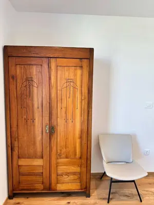 a wooden cabinet and a white chair in a room at Angel Wings premium apartment in Ljubljana