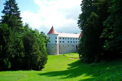 a large white building with a red roof on a green field at Apartment House Sumrak in Bizeljsko