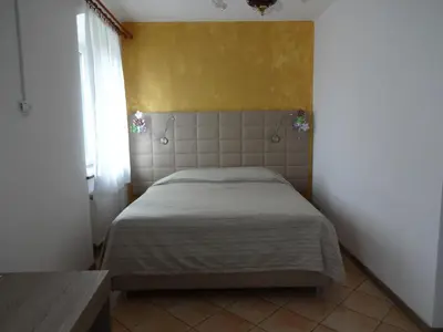 a small bedroom with a bed with a yellow wall at Fedrig Private Rooms & Apartment in Kobarid