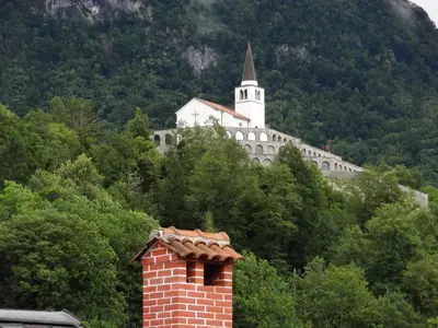 a building on top of a hill with a church at Fedrig Private Rooms & Apartment in Kobarid