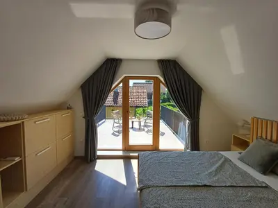 a bedroom with a bed and a window with a patio at Vineyard cottage Kraljevi kotiček in Trebnje