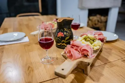 a wooden table with a glass of wine and a plate of food at Vineyard cottage Kraljevi kotiček in Trebnje