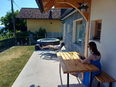 a woman sitting on a picnic table with a laptop at Vineyard cottage Kraljevi kotiček in Trebnje