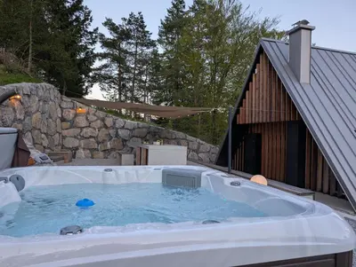 a hot tub in a yard next to a building at Pine Hill RUBY with free jacuzzi in Rakitna