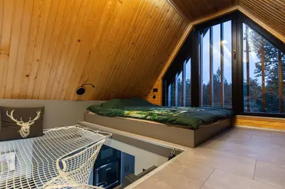 a bedroom with a bed and a large window at Pine Hill RUBY with free jacuzzi in Rakitna
