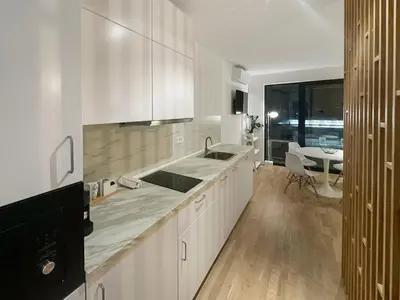 a kitchen with white cabinets and a sink and a table at Apartment number 7 in Ljubljana