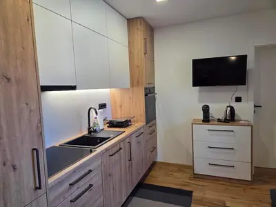 a kitchen with white cabinets and a sink and a tv at Vila Natalia in Kranjska Gora