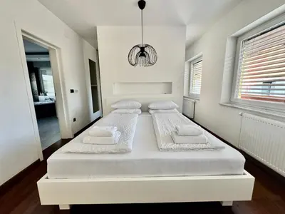 a white bedroom with two beds and a chandelier at Vila SofiOmi in Bled