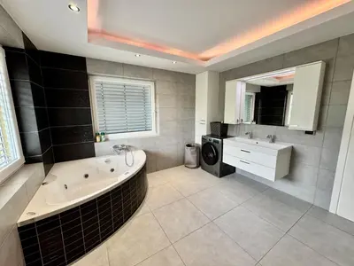 a bathroom with a tub and a sink and a washing machine at Vila SofiOmi in Bled