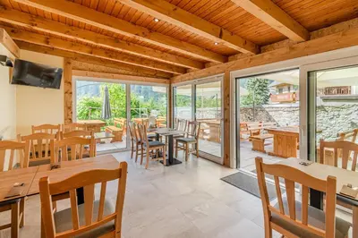 a dining room with tables and chairs and windows at Pension Hosnar, apartma Gusto in Bovec